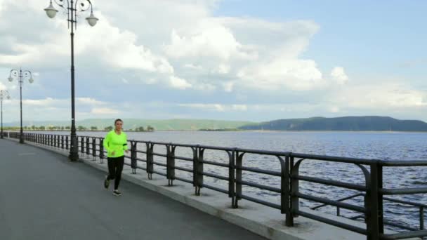 Caucásica morena mujer en tela deportiva corre en terraplén cerca del río — Vídeo de stock