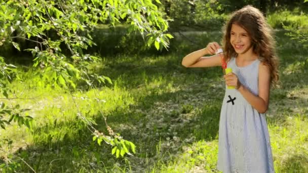 Felice bambina che gioca bolle di sapone umido all'aperto, ridendo e sorridendo — Video Stock