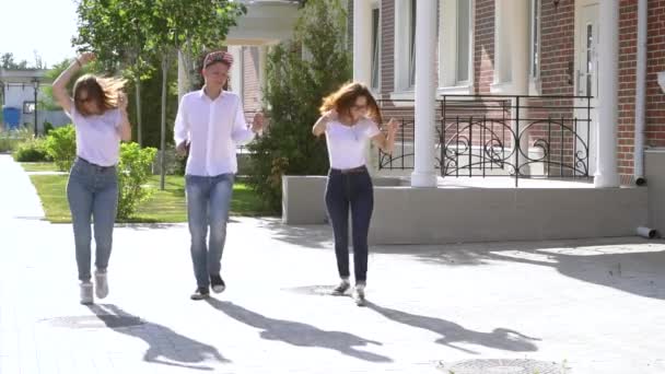 Three girls and boy dressed in similar jeans and shirts dancing in the street — Stock Video