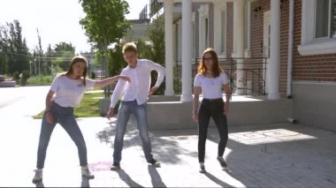 Üç kız ve erkek benzer kot pantolon ve gömlek sokakta dans giymiş