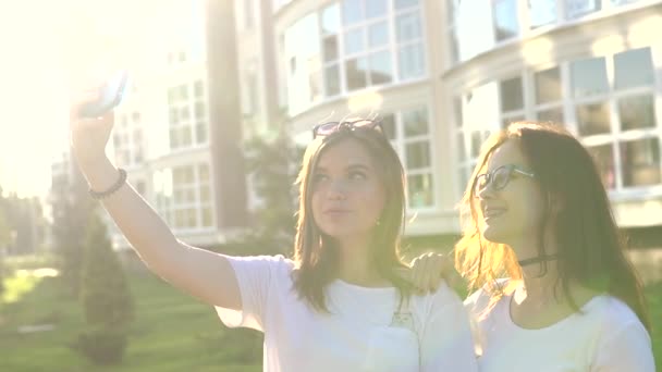 Belle ragazze amici prendendo selfie in città tramonto forte luce posteriore — Video Stock