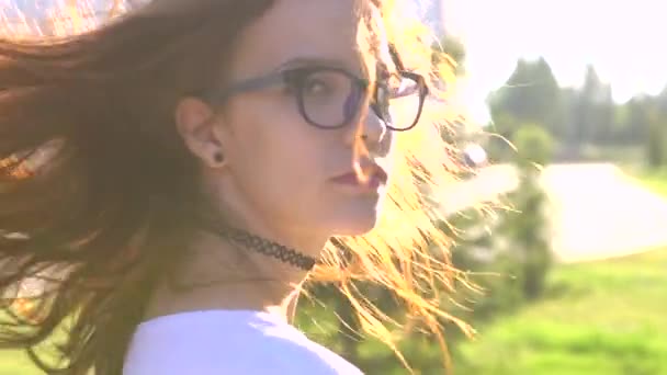 Відео портрет дівчини-підлітка в окулярах, що ходять в парку, трясе волосся — стокове відео