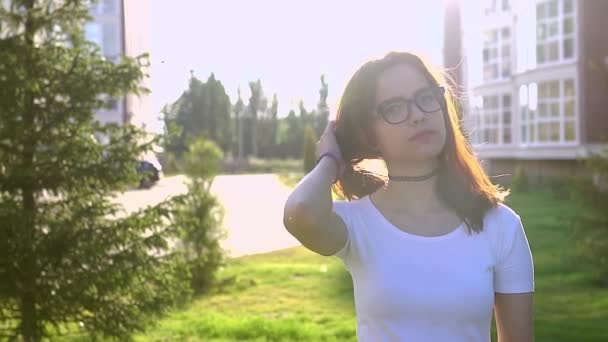 Video retrato adolescente usando gafas caminando en el parque sacudiendo el pelo — Vídeo de stock