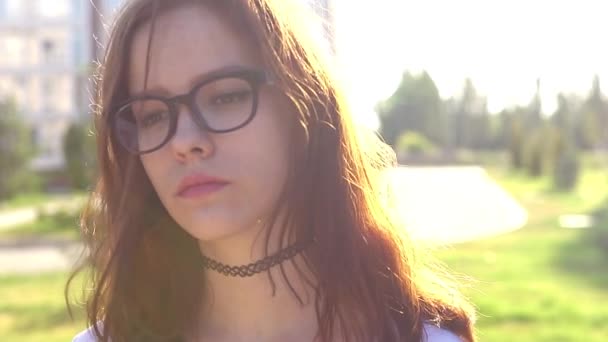 Vidéo portrait adolescente portant des lunettes marchant dans le parc secouant les cheveux — Video