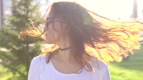 Video retrato adolescente usando gafas caminando en el parque sacudiendo el pelo — Vídeos de Stock