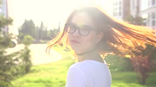 Video retrato adolescente usando gafas caminando en el parque sacudiendo el pelo — Vídeo de stock