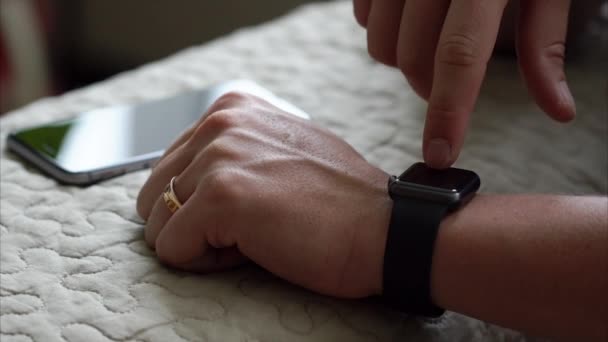 Молодой человек с помощью своего приложения для умных часов закрывает руки — стоковое видео