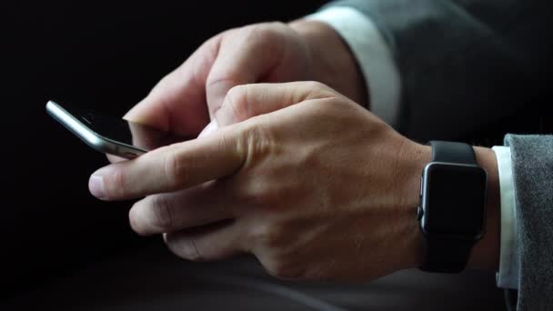 Hombre de negocios usando texto de escritura de teléfonos inteligentes usando relojes inteligentes en su mano — Vídeo de stock