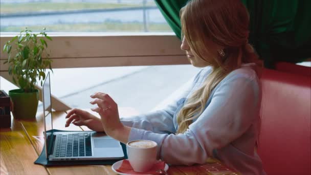 Jonge mooie zakenvrouw, werken met de laptop in café — Stockvideo