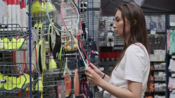 Shopper féminin choisit des raquettes de badminton dans le magasin d'articles de sport — Video