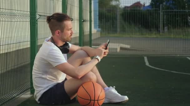 Sportsman browsing news in mobile phone during break time in basketball — Stock Video