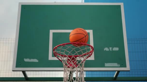 Humano irreconhecível está jogando basquete, batendo a bola em um aro — Vídeo de Stock