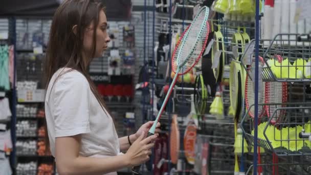 Jonge vrouw koopt badminton rackets in sportwinkel — Stockvideo