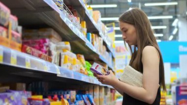 Genç bir kadın marketten bisküvi alıyor.