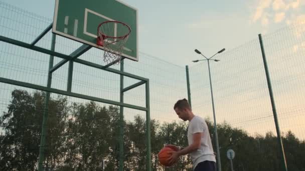 Deportista está lanzando pelota en la canasta en la cancha de streetball abierto — Vídeos de Stock