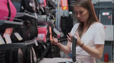 Genç bir bayan spor mağazasından spor çantası alıyor.