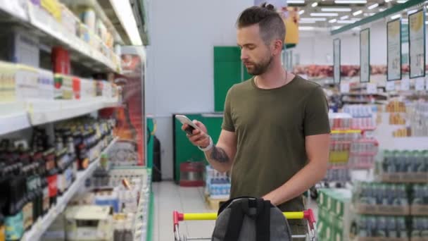 Shopping nel supermercato, l'uomo sta visualizzando la lista di acquisto nel telefono — Video Stock