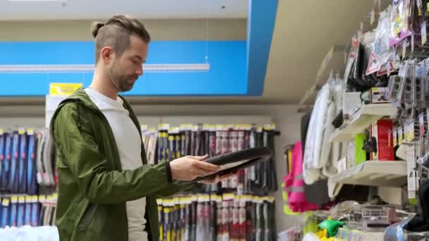 Молодой парень покупает крышку рулевого колеса в специальном магазине — стоковое видео