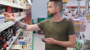 TOLYATTI, RUSSIA - 15 Temmuz 2020: Süpermarkette alışveriş, insan internetteki bira hakkında bilgi arıyor