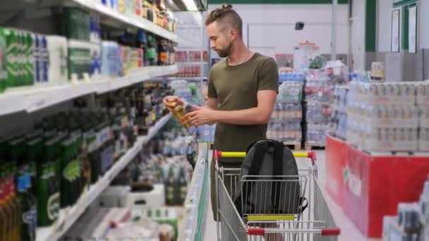 Молодий чоловік купує пиво в гіпермаркеті — стокове відео