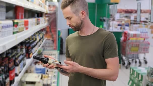 L'uomo sta controllando la birra per applicazione nello smartphone nel supermercato — Video Stock