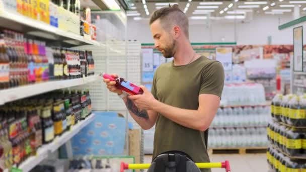Młody facet kupuje piwo w supermarkecie. — Wideo stockowe