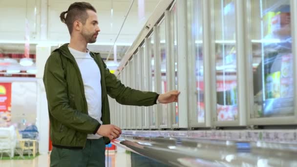 Hombre comprando comida congelada en el supermercado — Vídeos de Stock