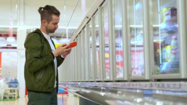 Markette alışveriş yapan erkek süpermarkette dondurulmuş yiyecek seçiyor.
