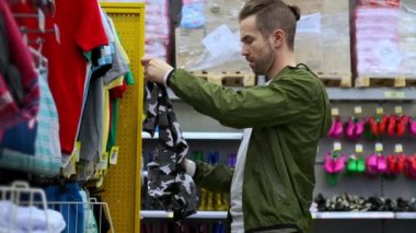 Genç adam bir mağazadan tişört alıyor.