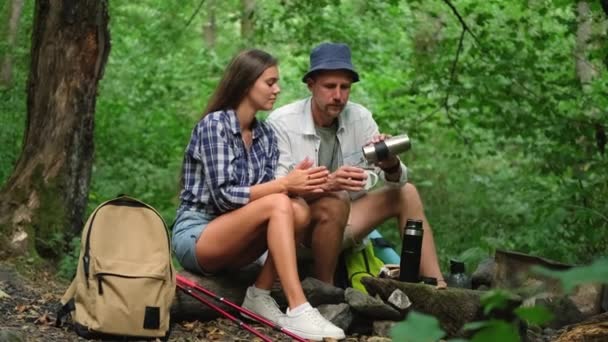 Dva turisté odpočívají na odpočinku v lese, muž a žena pijí čaj — Stock video