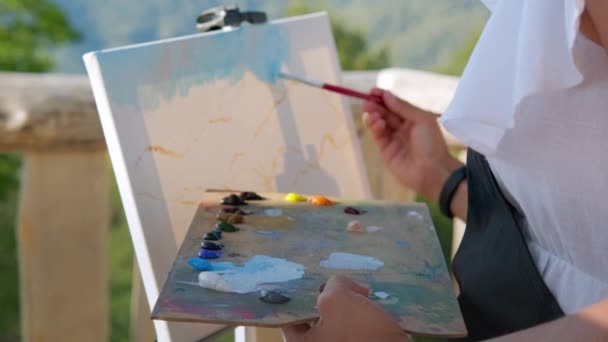 Onbekende vrouwelijke schilder creëert een beeld met berglandschap — Stockvideo