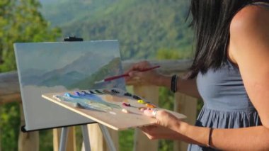 Bilinmeyen kadın ressam açık havada dağ manzarası çiziyor.