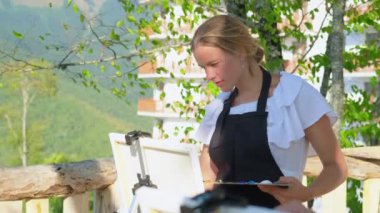 Kadın ressam açık havada resim üzerinde çalışıyor.