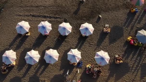 Urlauber relaxen unter Sonnenschirmen am Strand, Antenne — Stockvideo