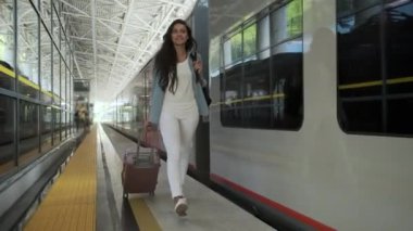 Kadın tren istasyonunda bavulla yürüyor.