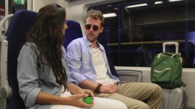 Trenle seyahat eden turistler vagonda oturuyorlar.