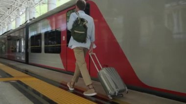 Tren istasyonundaki platformda yürüyen genç adam.