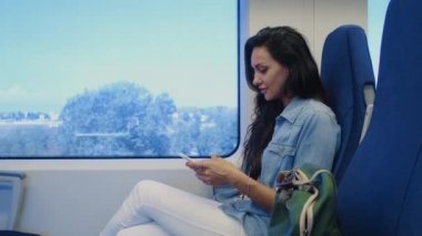 Tren yolculuğu sırasında cep telefonunda sohbet eden bir kadın.