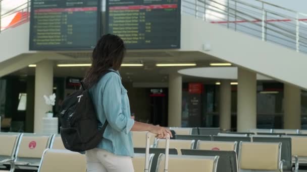 Touristin vor der Abflugtafel im Terminal des internationalen Flughafens — Stockvideo