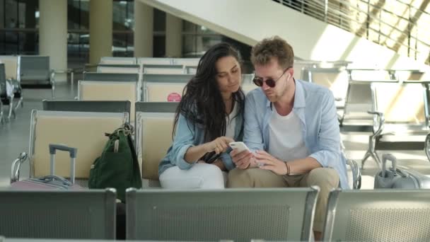 Dejligt par med kufferter sidder i lobbyen på banegården – Stock-video
