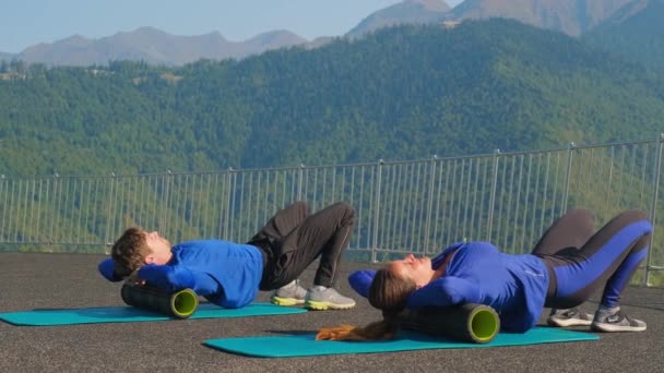 Entrenamiento con rodillos de masaje, atletas masculinos y femeninos están masajeando espalda, liberación automiofascial — Vídeos de Stock