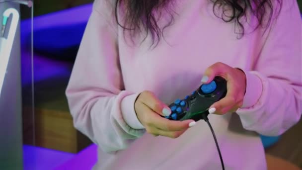 Mujer joven sosteniendo un controlador de juego negro en la sala de juegos — Vídeos de Stock