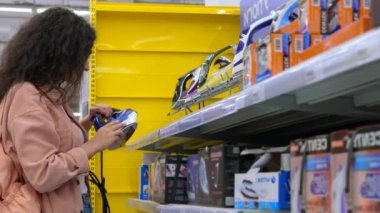 Kadın müşteri elektrikli ütüyü ev aletleri mağazasında tercih ediyor.