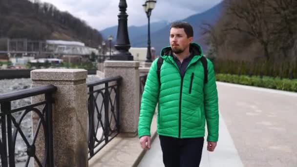 Caminar en la ciudad en primavera u otoño día, el hombre está paseando solo en el terraplén de la ciudad — Vídeo de stock