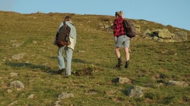 Lezení na vrcholu hory dvou samic Backpackers — Stock video