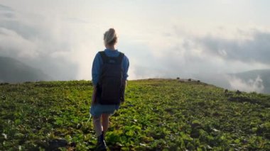 Dişi sırt çantalı bulutların tepesinde doğa yürüyüşü ve seyahati yapıyor.