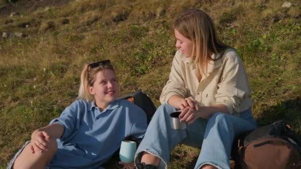 Девушки-туристы разговаривают за чашкой чая во время похода — стоковое видео