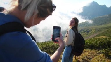 Mutlu genç kadın Mobil fotoğraf için dağda poz veriyor, yazın seyahat ediyor.