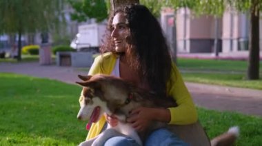 Mutlu kadın parkta sevimli köpeğini okşuyor.