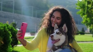 Esmer kadın ve şirin köpekleri telefonla fotoğraf çekiyorlar.